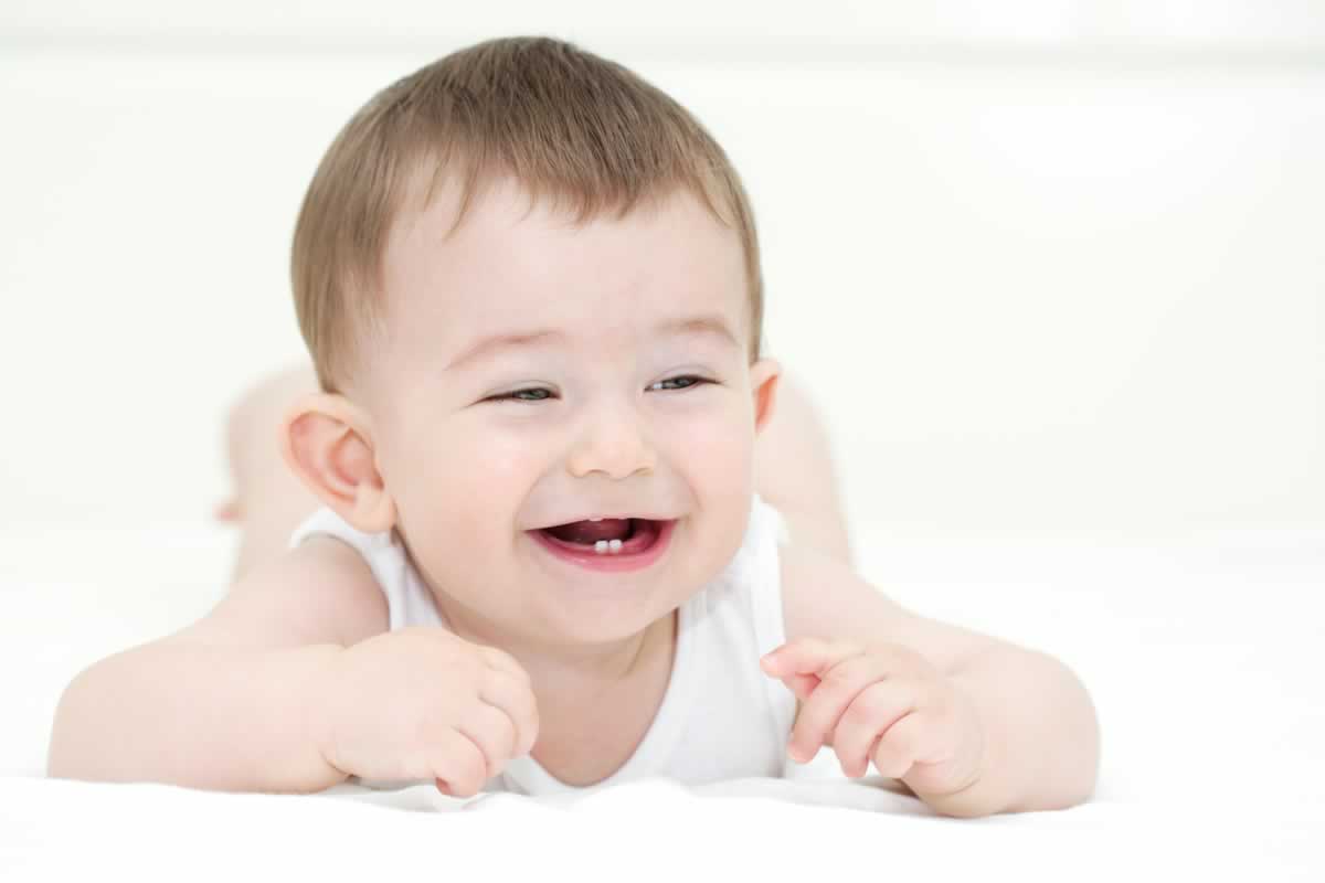 A happy baby with healthy teeth. It is important to make a habit of brushing the teeth when a baby grows the first teeth.