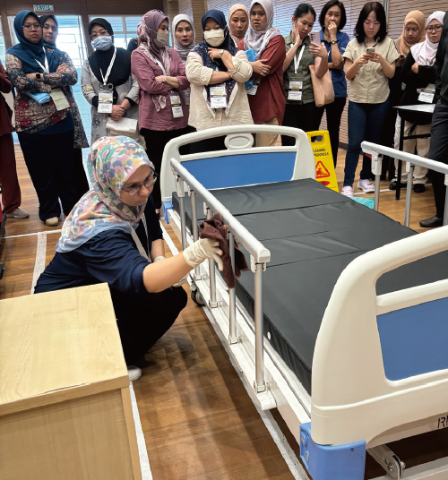 Participant cleaning a bed in a surface cleaning practice