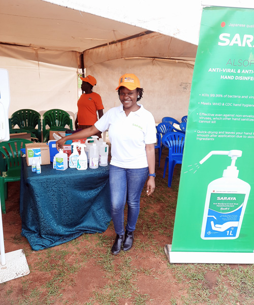 Ms. Aber Beryl, staff member of Saraya Manufacturing Uganda, posing in front of SARAYA's stand during the event.