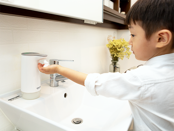 Child placing hands under Wash Bon Auto Dispenser to dispense soap for washing hands